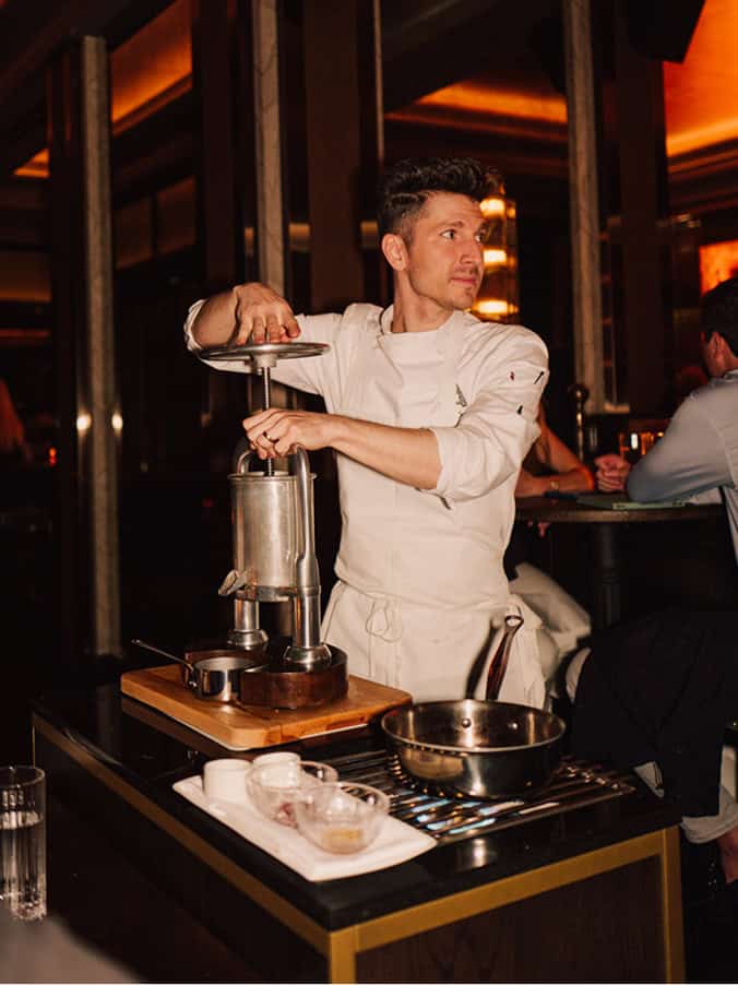 Chef Jenner Tomaska working on a dish next to a table