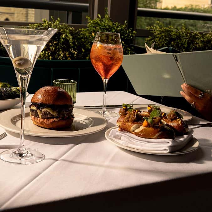 Gourmet burger and appetizers with drinks on a restaurant table.