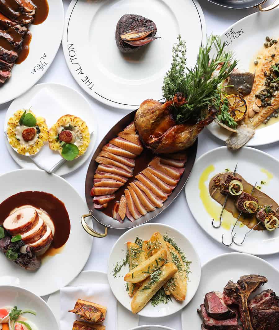 Elegant gourmet dishes served on white plates at The Alston restaurant.