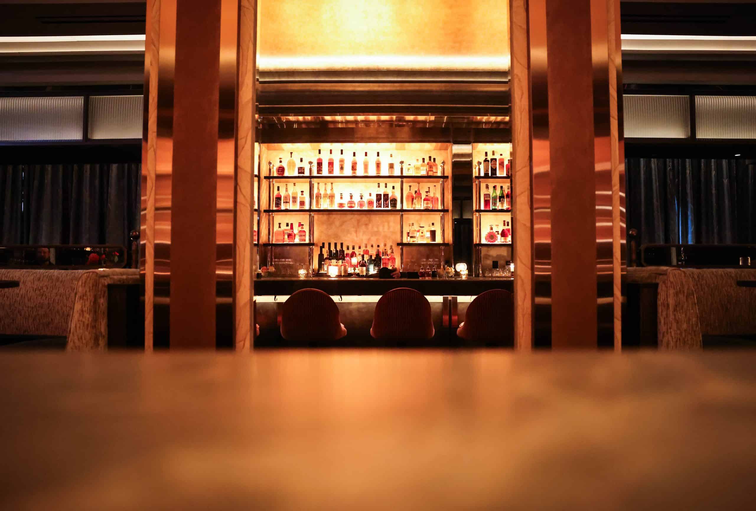 Elegant bar with illuminated shelves and seating at The Alston.